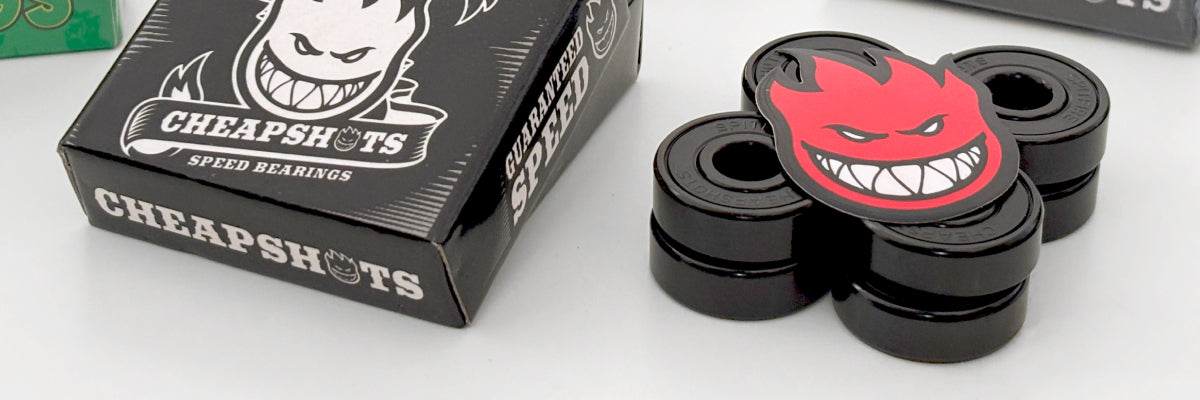 A set of four black Spitfire Cheapshots bearings with a red devil face sticker, shown next to their black packaging box.