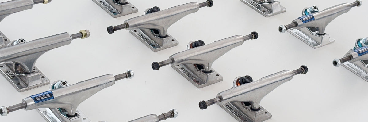 Multiple silver metal skateboard trucks arranged diagonally on a clean white background.